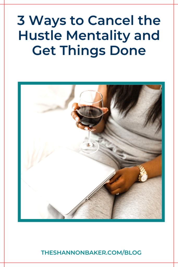 A woman holding a glass of red wine with a Mac laptop on her legs and the image says "3 Ways to Cancel the Hustle Mentality and Get Things Done"